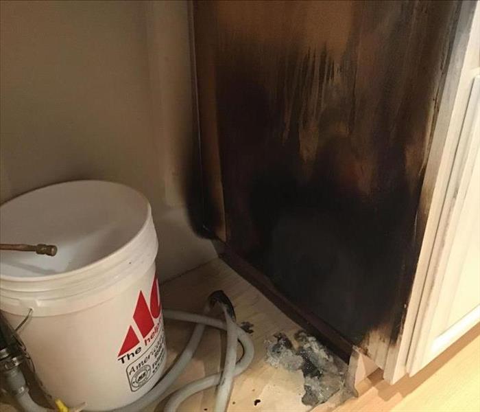 white circular bin next to a cabinet that is black from fire 