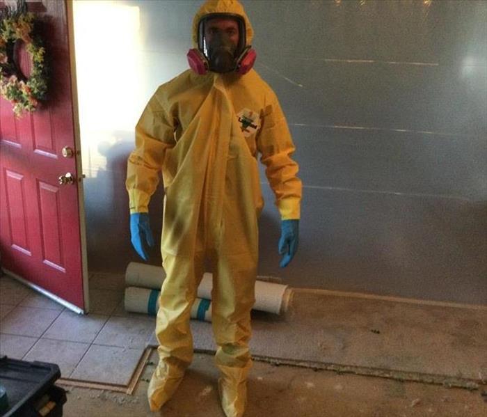 male wearing a full coverage of yellow ppe suit with a mask and blue gloves in a property